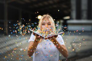 girl blowing confetti from an open book